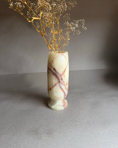 Marble-patterned vase with dried gold branches on a gray background