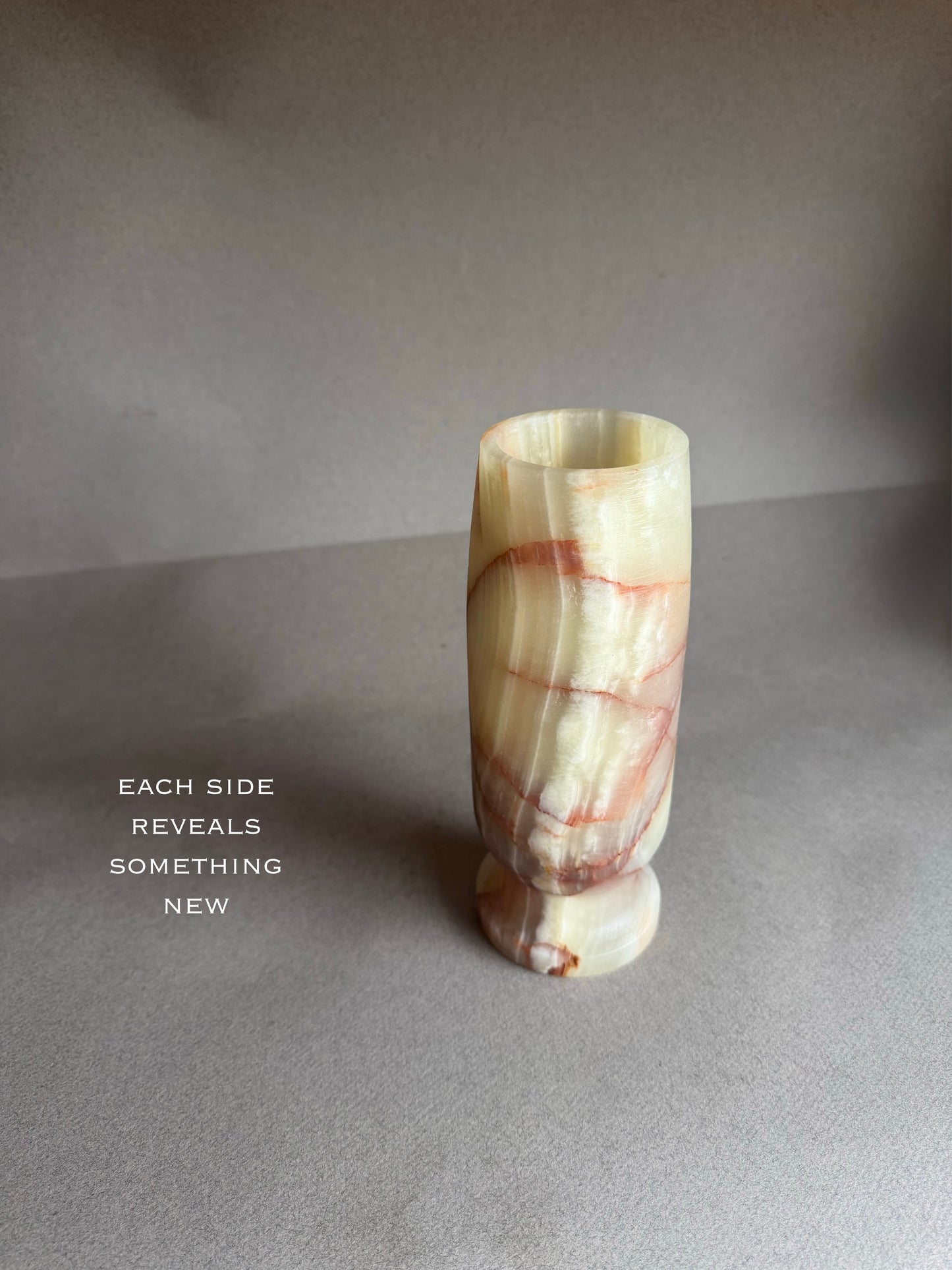 Marble-textured vase on a gray surface with a quote