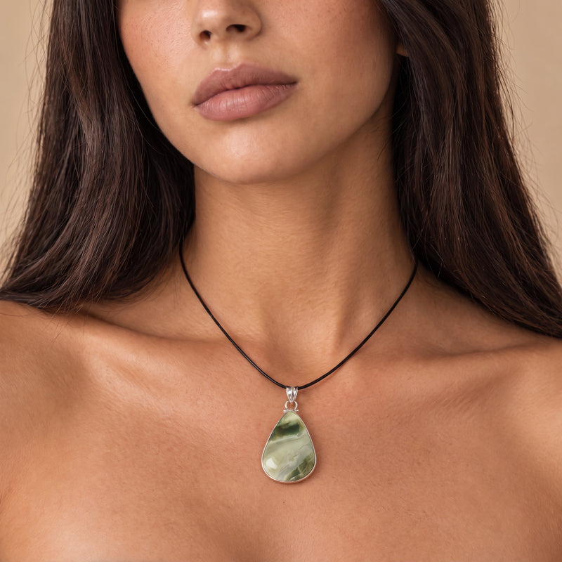 Sage green and cream serpentine teardrop pendant in sterling silver on a short black cord, worn at the collarbone
