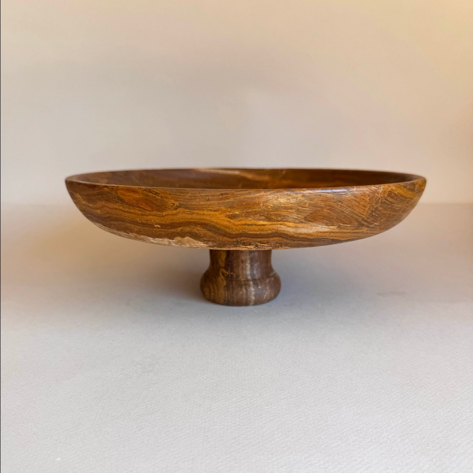 Wooden bowl with a pedestal base on a plain background