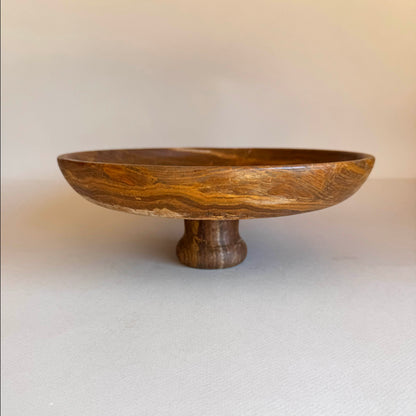 Wooden bowl with a pedestal base on a plain background
