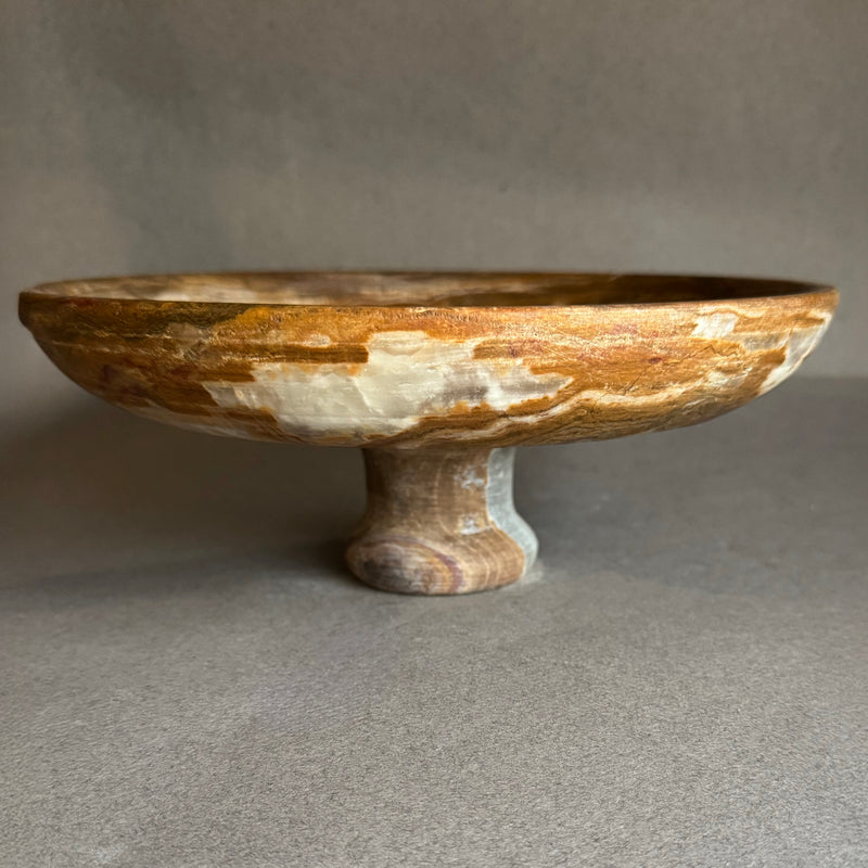 Hand-carved onyx pedestal bowl with cream, honey, and walnut veining, wide shallow form and pedestal base, natural stone fruit bowl and centerpiece.
