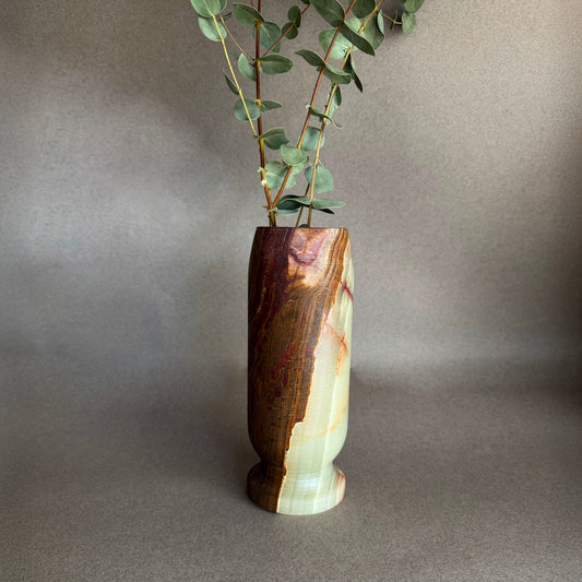 Brown green raw onyx natural stone vase with a natural grain pattern on a gray background