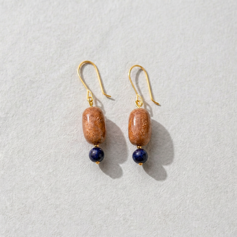Pair of earrings with sunstone orange beads and blue sodalite stones on a light gray background