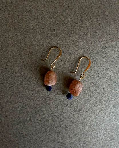 Pair of earrings with brown beads and gold hooks on a gray background Gold filled gemstone earrings with raw sunstone and deep blue sodalite accent
