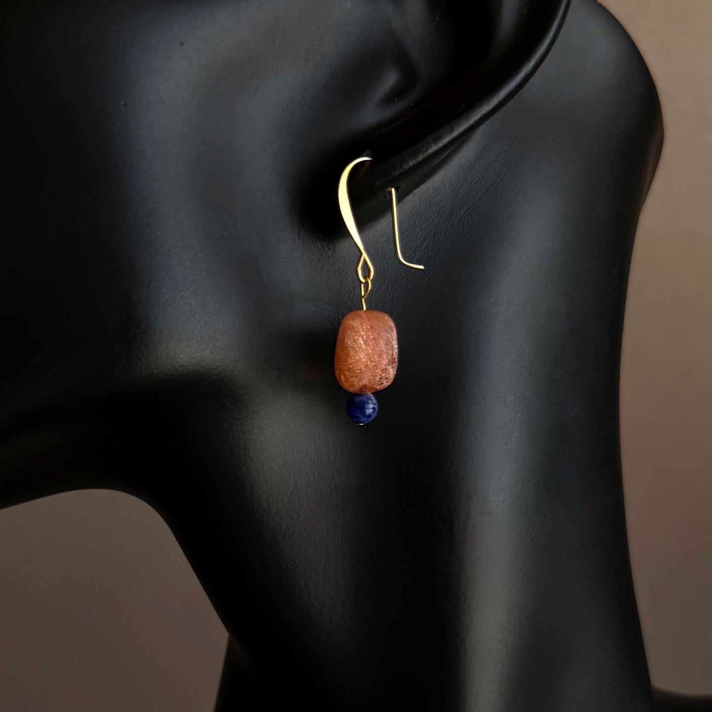 Earring with a orange bead and blue stone on a black mannequin. Handmade sunstone and sodalite drop earrings on gold filled hooks, minimalist gemstone jewelry
