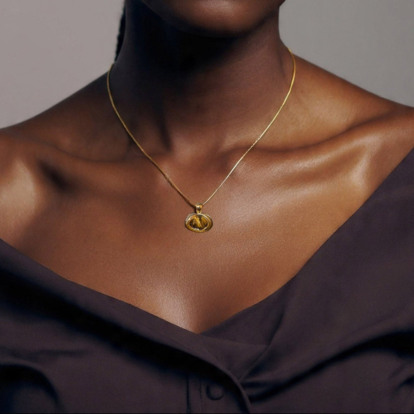 Woman wearing a gold necklace against a neutral background