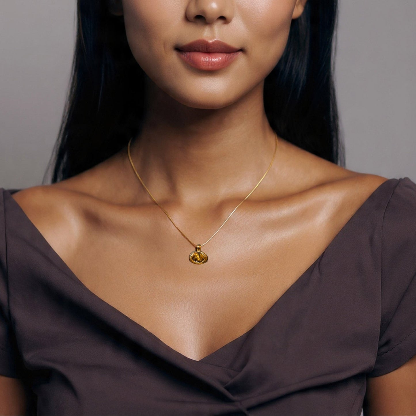Woman wearing a gold necklace with a heart pendant against a neutral background