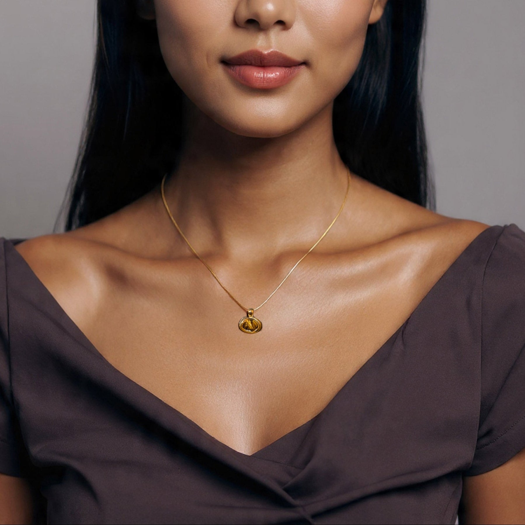 Woman wearing a gold necklace with a heart pendant against a neutral background