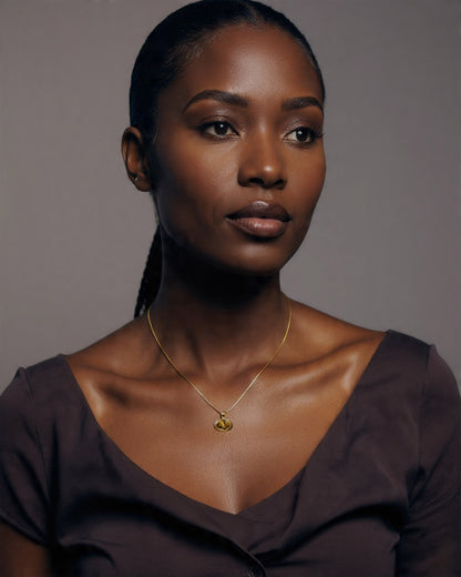Woman wearing a gold necklace against a gray background