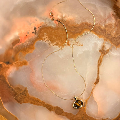 Gold necklace with a pendant on a marble surface