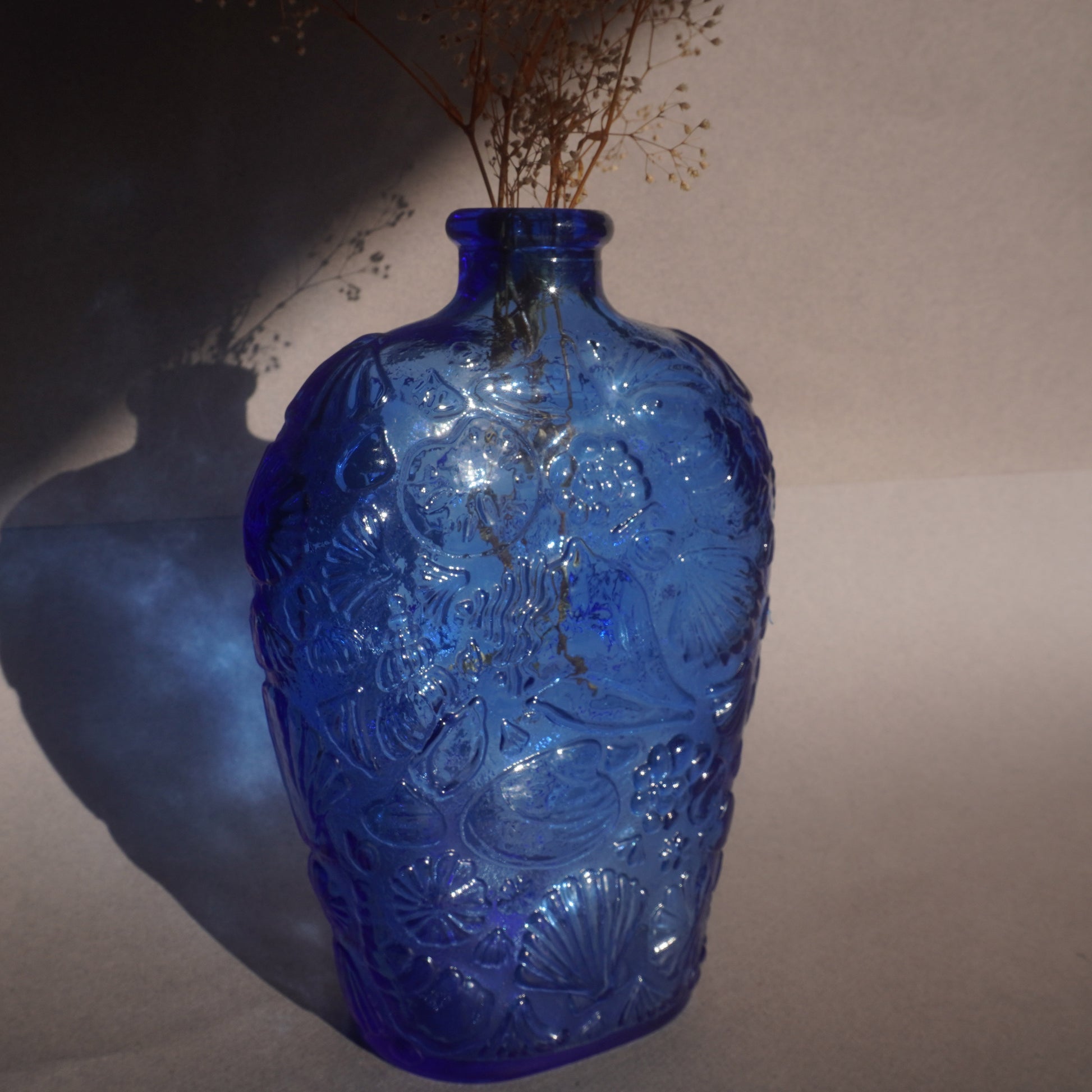 Blue glass vase with intricate patterns on a plain background