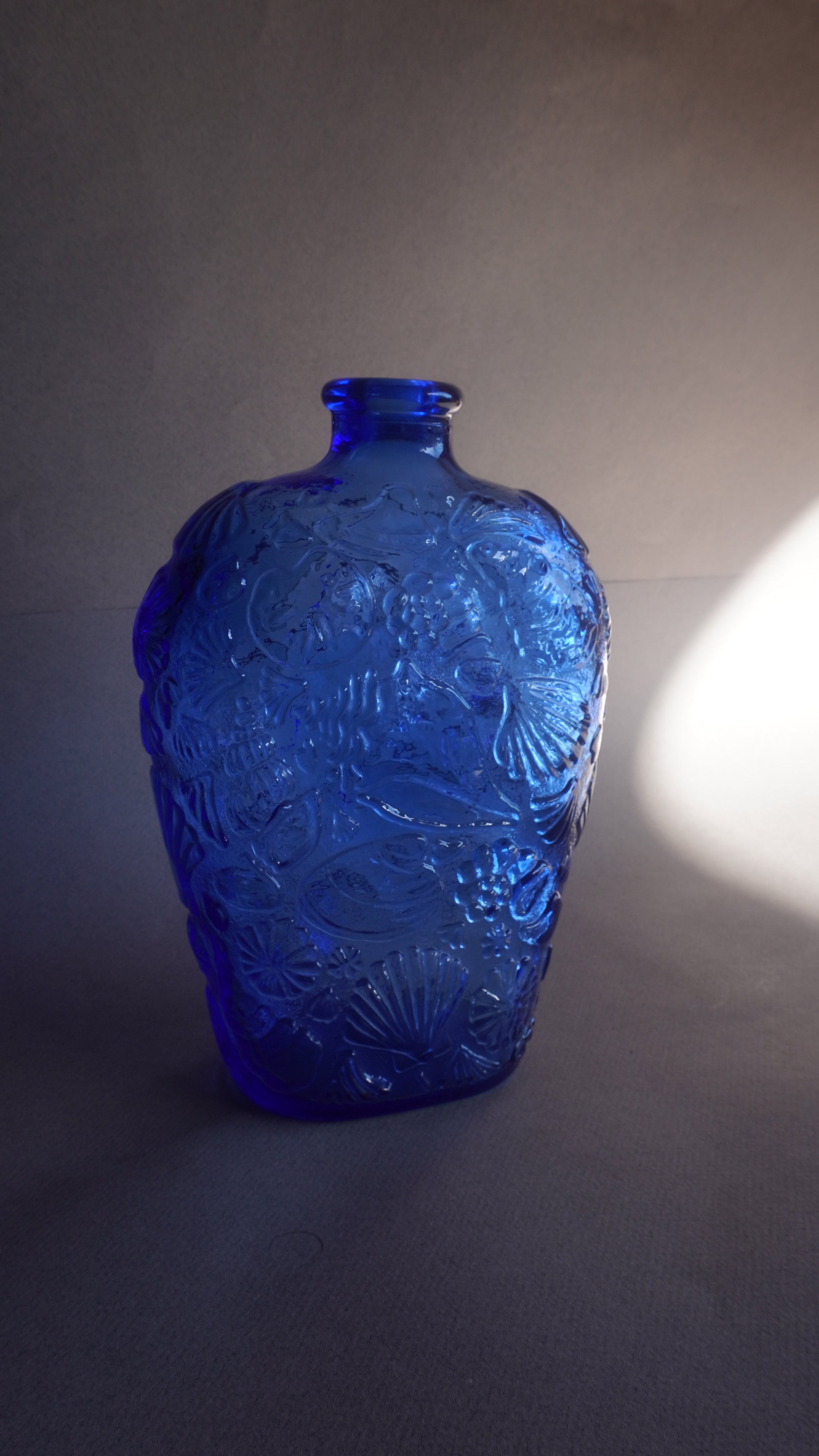 Blue glass bottle with intricate patterns on a gray background