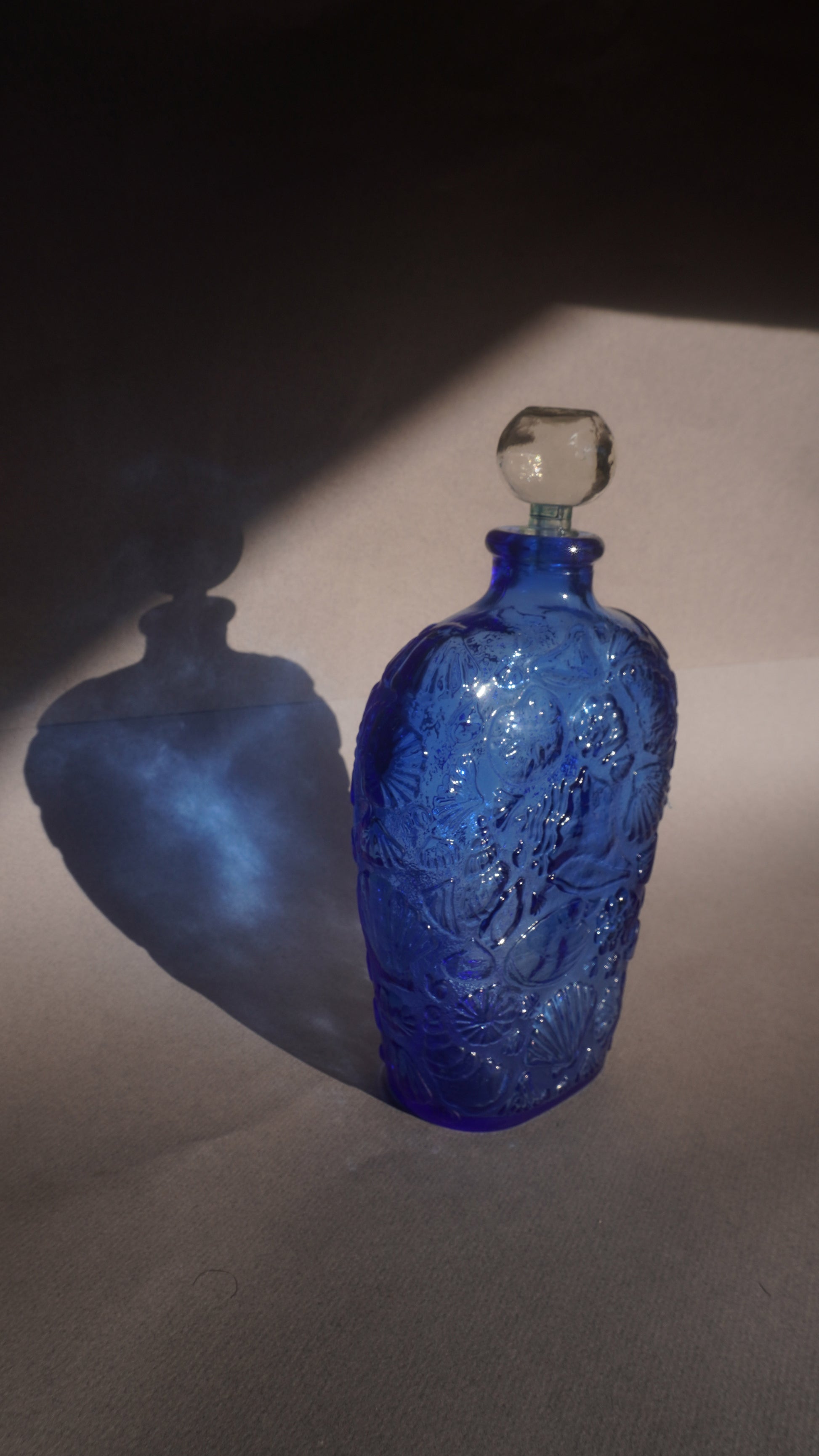 Blue glass decanter with intricate design on a gray background