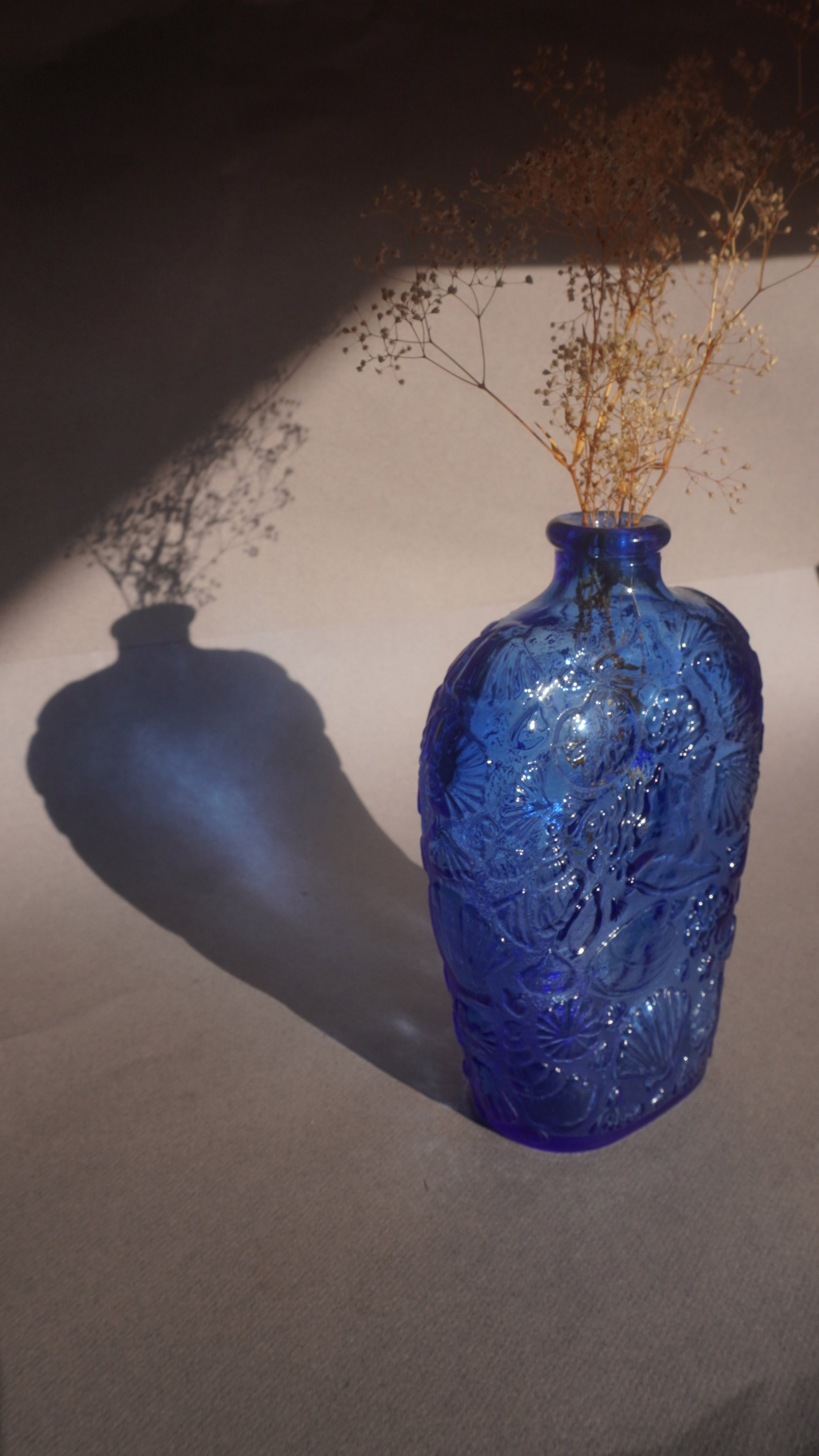 Blue textured vase with dried flowers on a light background