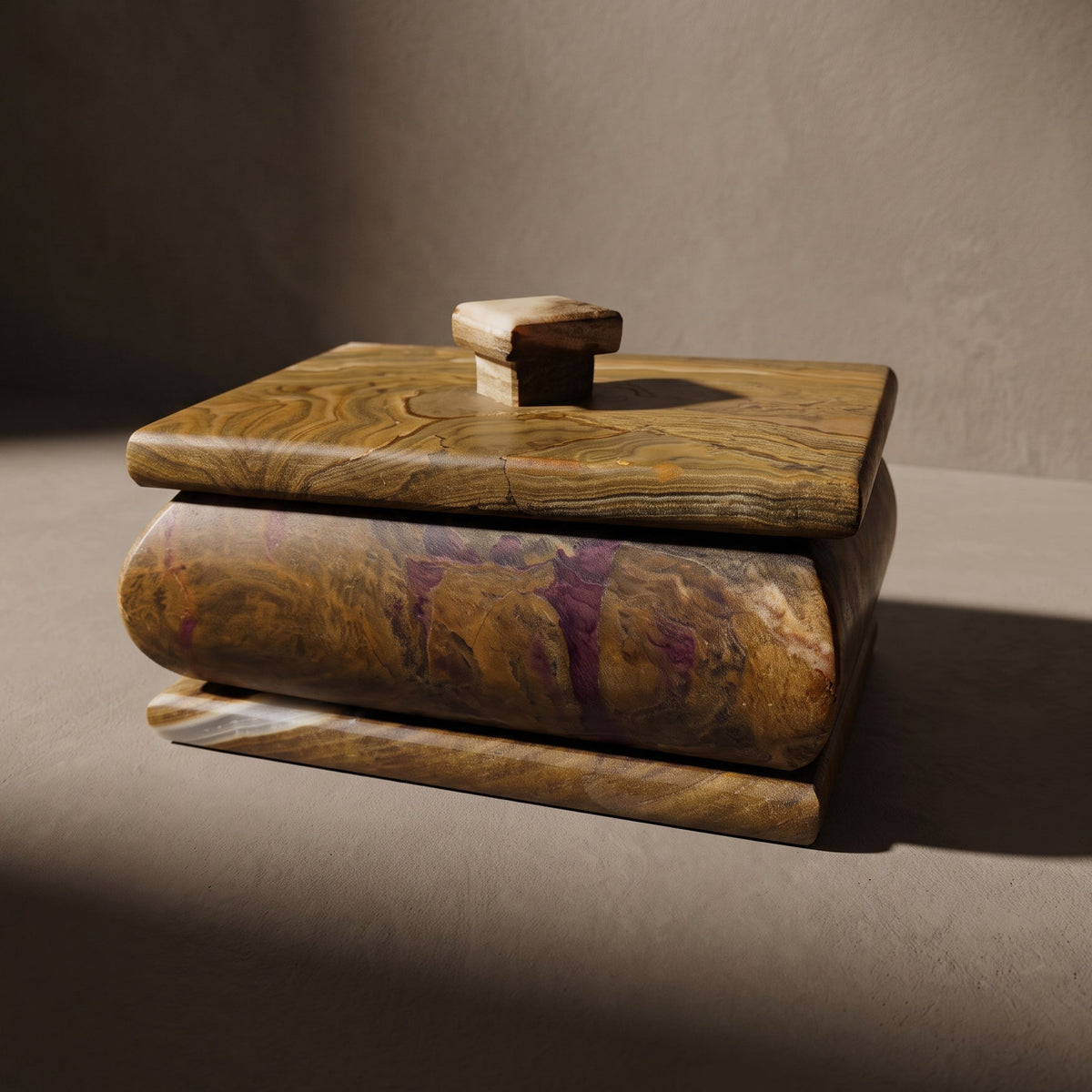 Side profile of the hand-carved onyx keepsake box, streaks of plum running through the honey and walnut body beneath a wood-grain lid with a square knob