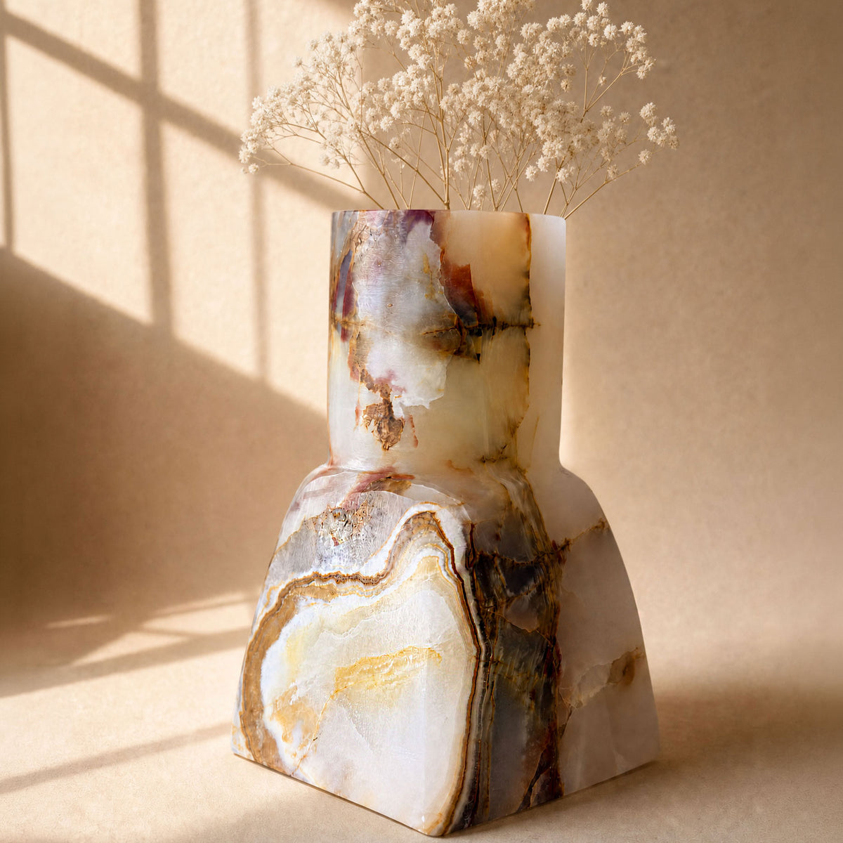 Geometric white onyx vase with amber and rust veining and concentric blooms, in window light

