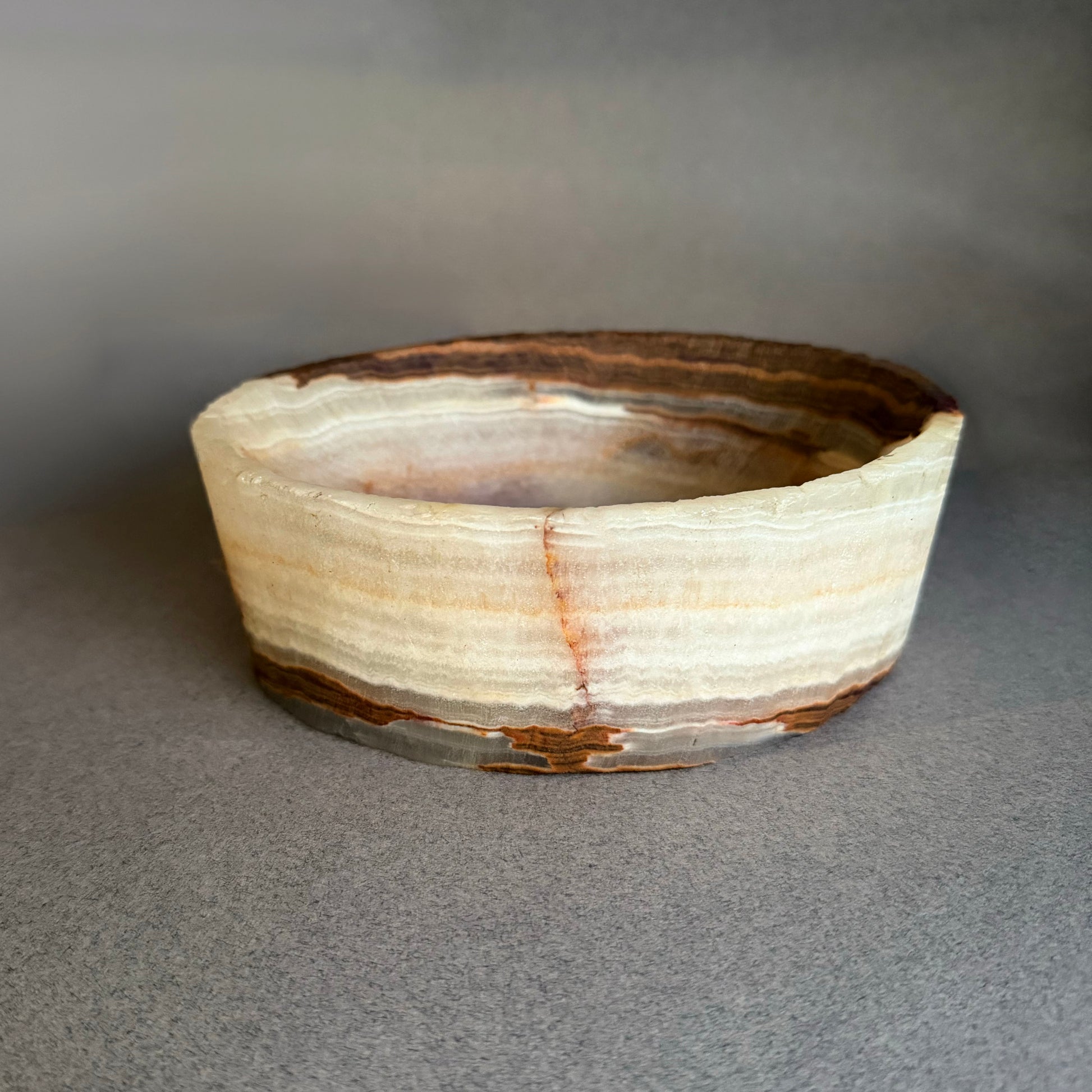 Top view of white onyx catchall bowl featuring warm brown and honey veining in raw natural stone
