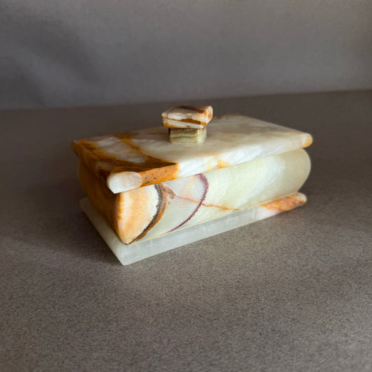 Open hand carved onyx jewelry box revealing smooth stone interior and natural patterns
