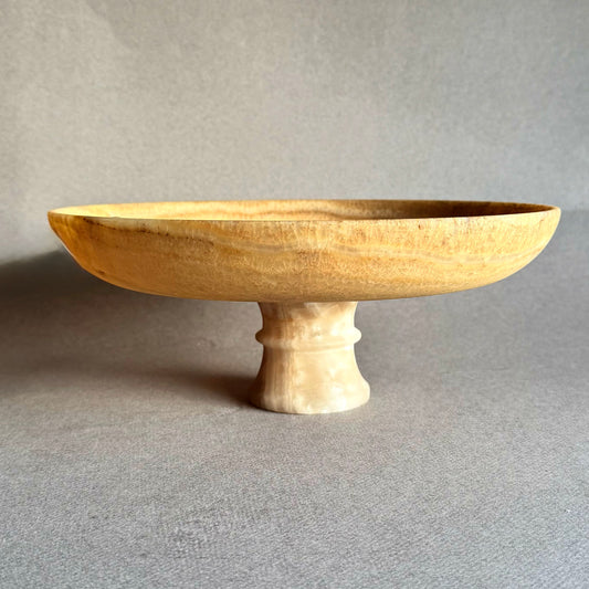 Golden honey onyx pedestal bowl with warm amber tones on neutral background
